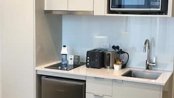 A compact kitchen with a dishwasher, a microwave, a toaster, and a sink.
