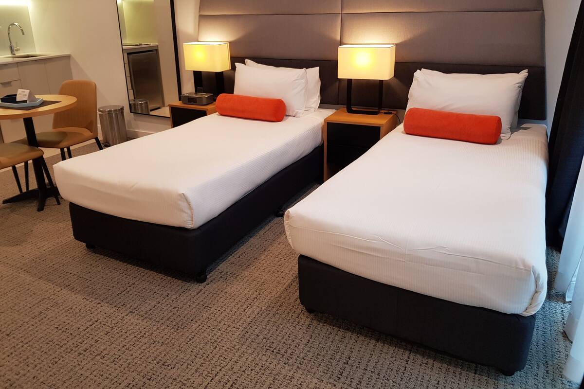 A hotel room with two beds, a desk, and a chair.