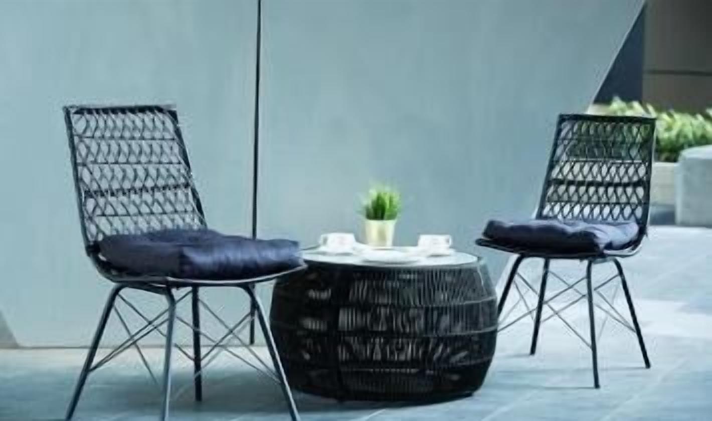 Two black wicker chairs with blue cushions and a round black table with a small plant.