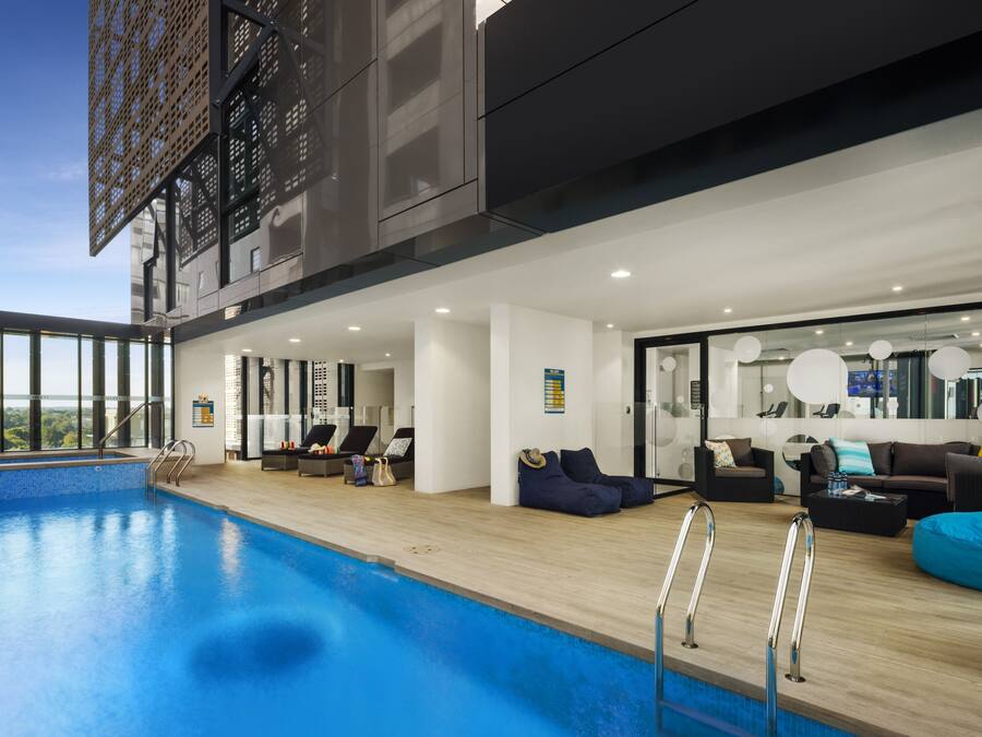 Uma área interna de piscina moderna com vista para a cidade, equipada com sofás e uma mesa de centro.