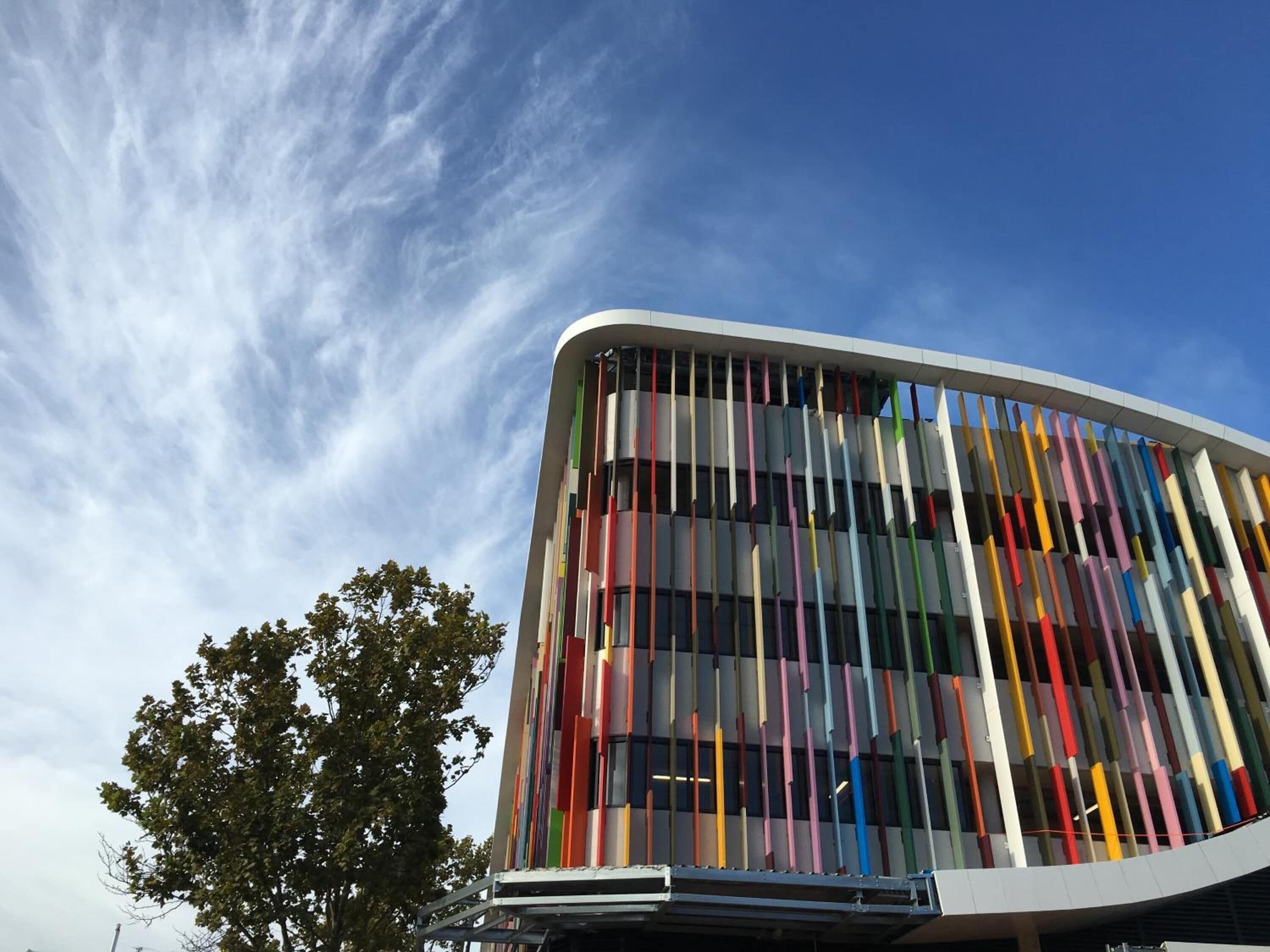 Un edificio moderno con fachada curva y listones verticales de varios colores.