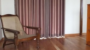 Ein Holzhocker mit Webstuhl-Rückenlehne in einem Raum mit Holzboden und Vorhang.