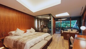 Un dormitorio moderno con tragaluz, una cama grande, una zona de estar y vistas al exterior.