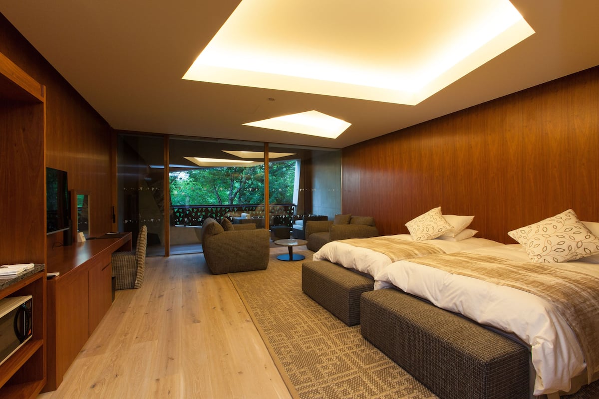 Un dormitorio moderno con una cama grande, dos sofás, una mesita y un televisor.