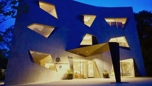 Un edificio moderno con recortes geométricos y una entrada de cristal.