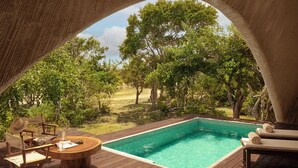 Una piscina exterior con cubierta de madera, rodeada de árboles y una vista despejada del paisaje.