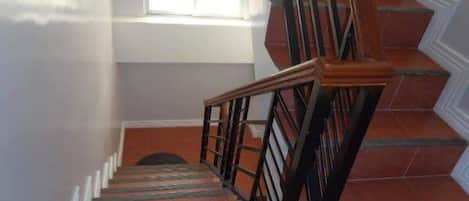 A staircase with wooden handrails and red-tiled steps leading to a landing.