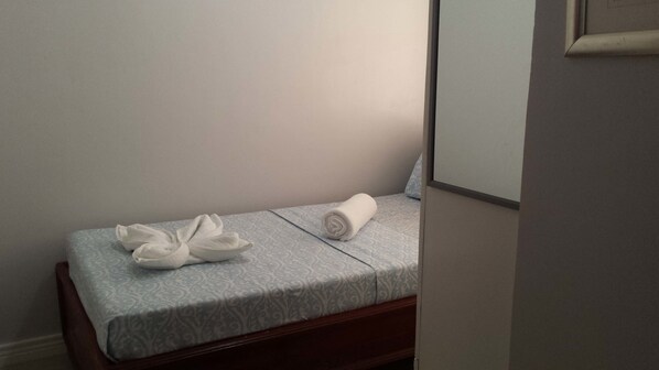 A neatly made bed with a patterned bedspread and two rolled towels. - Residenz Inn (Mandaue)