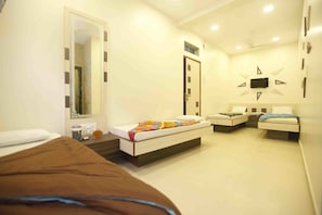 A hotel room with a large bed, a smaller bed, a desk, a chair, a mirror, and a TV mounted on the wall. - Hotel Al Moazin (Mumbai)