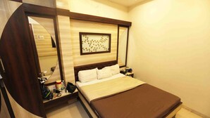 A bedroom with a bed, bedside tables, a mirror, and a wall-mounted artwork. - Hotel Al Moazin (Mumbai)