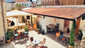 Un'area patio all'aperto con tavoli e sedie, piante in vaso e un tetto in tegole.