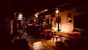 Zona bar scarsamente illuminata, con mobili in legno, una chitarra e un juke-box.