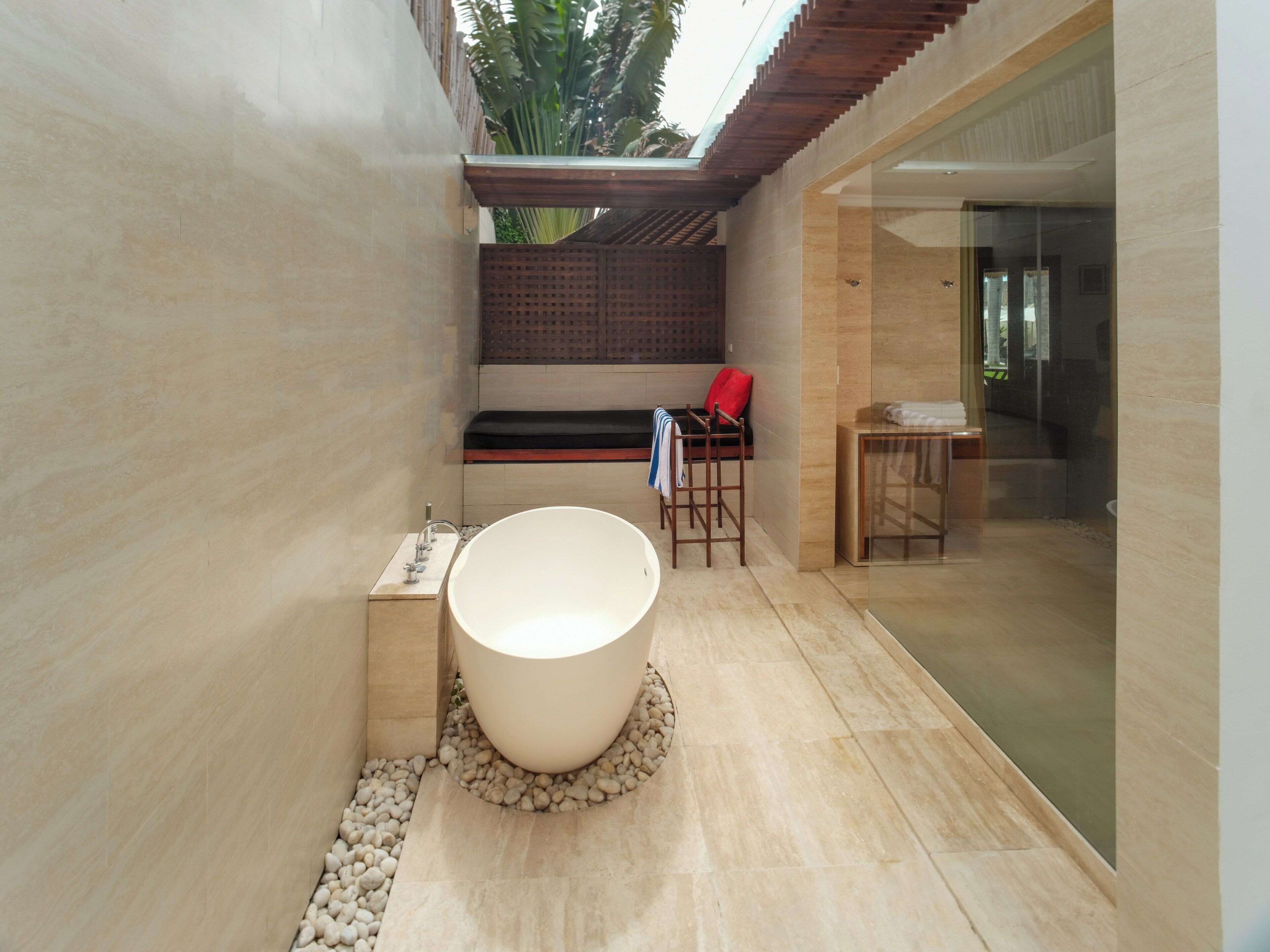 A modern bathroom with a large bathtub, a bench, and a glass shower enclosure.
