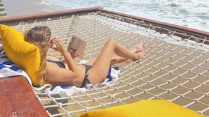 A person relaxing on a hammock with a view of the ocean and a clear sky. - Sunsea Resort (Mui Ne)