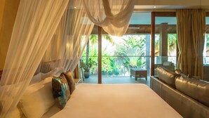 A bedroom with a large bed, a canopy, a sofa, and a view of greenery outside. - Sunsea Resort (Mui Ne)