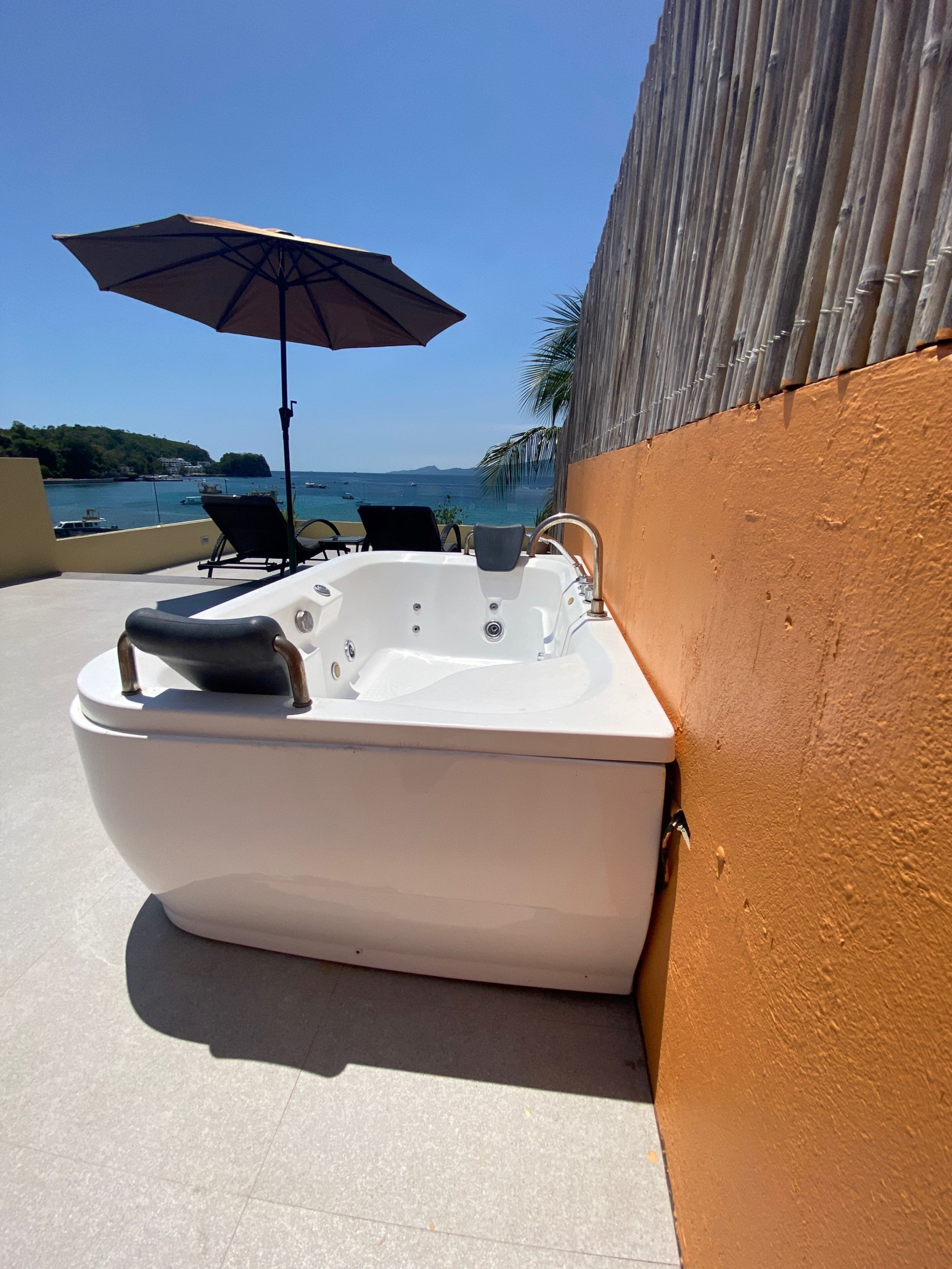 A hot tub on a balcony with a view of the sea and boats.