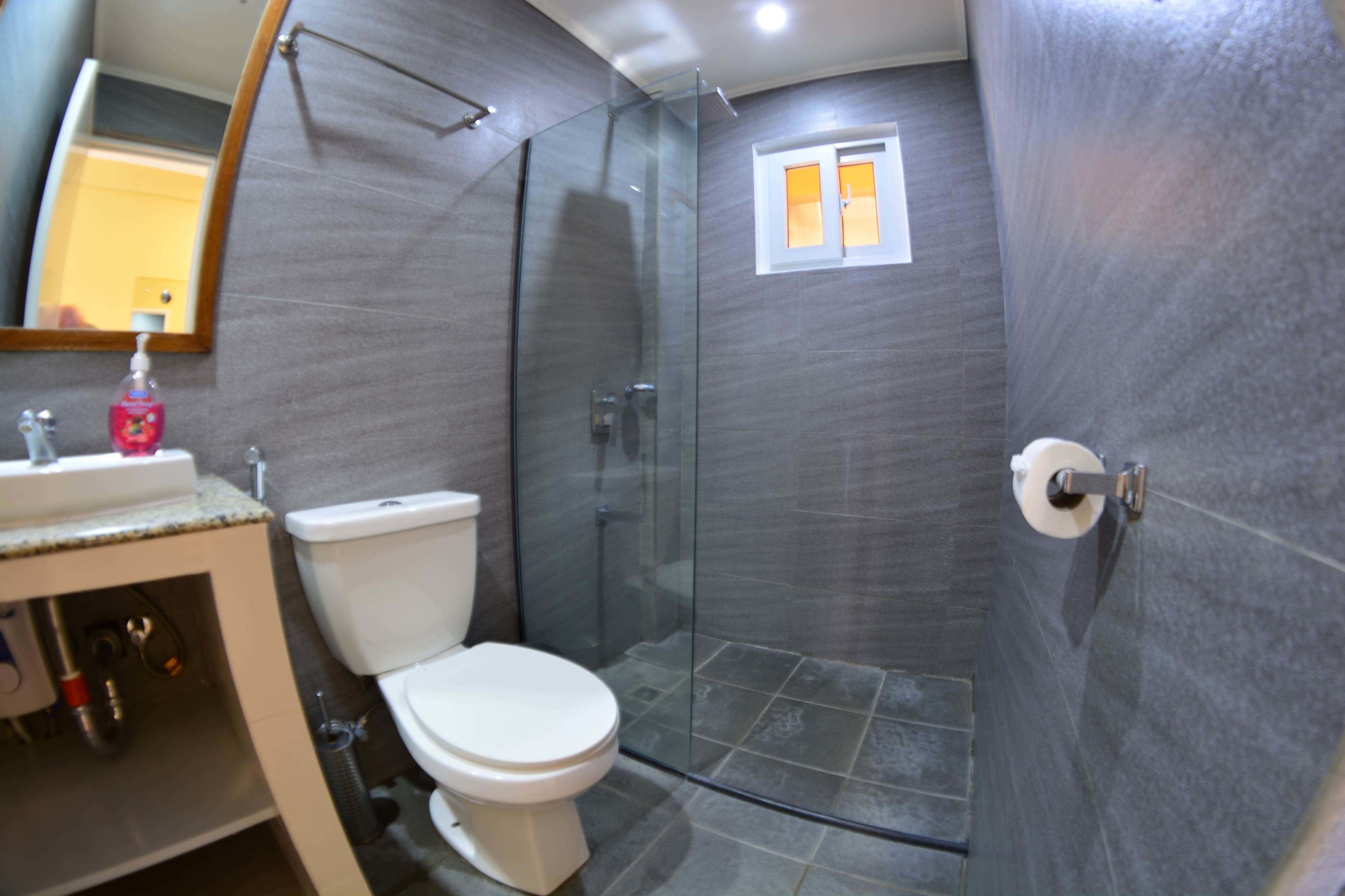 Un baño moderno con ducha acristalada, inodoro y lavabo con espejo.