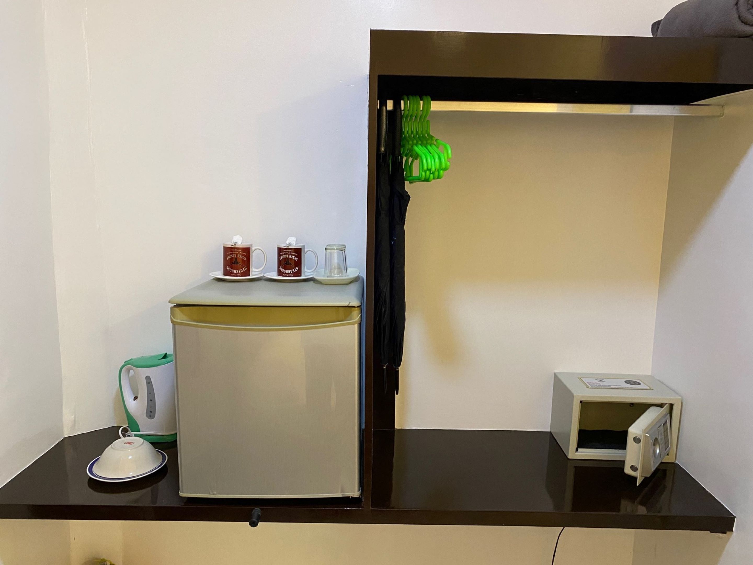 A kitchenette with a refrigerator, a microwave, a kettle, and a small cabinet.