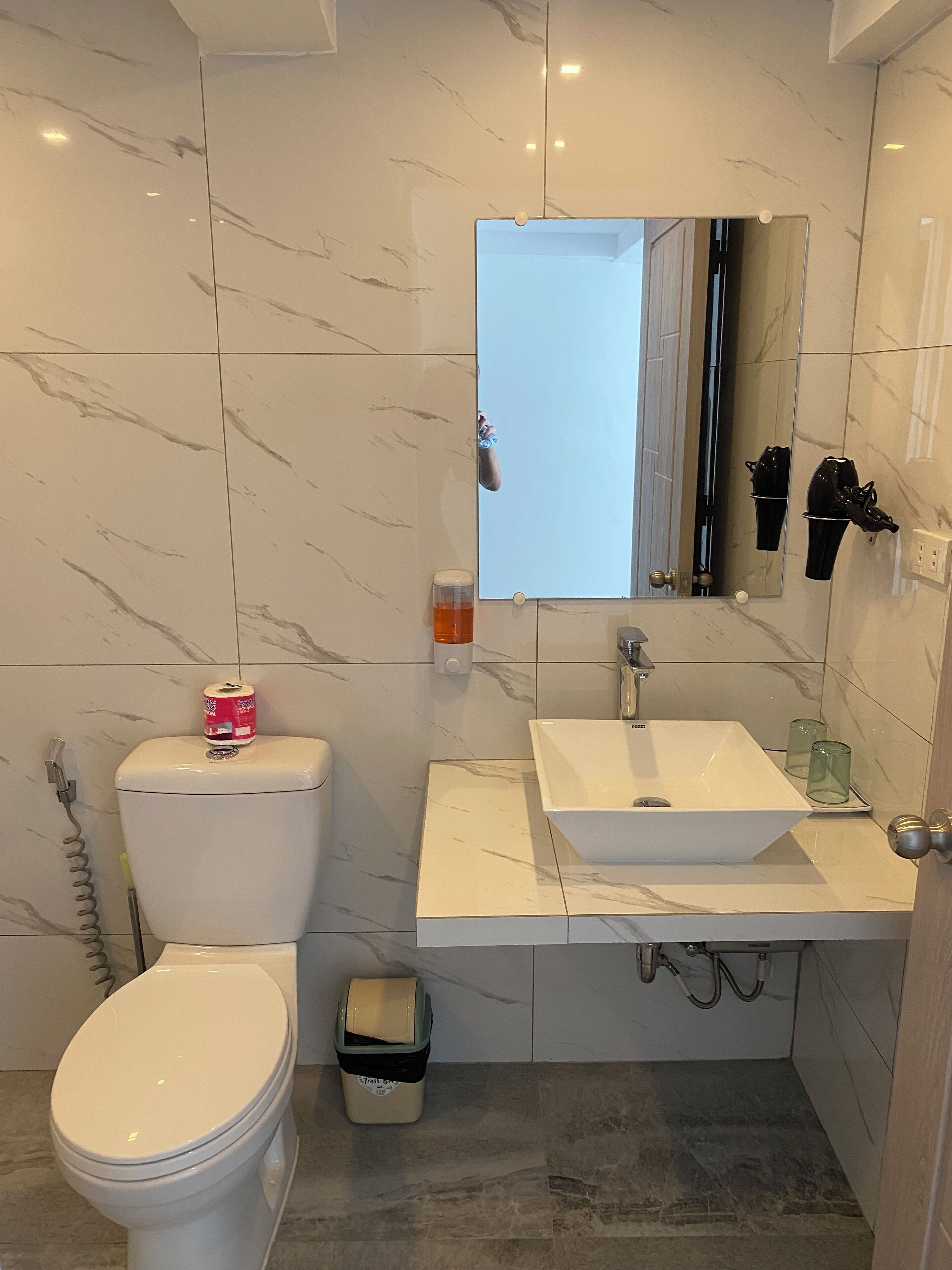 Un baño moderno con inodoro, lavamanos y espejo.