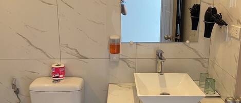Un baño moderno con inodoro, lavamanos y espejo.