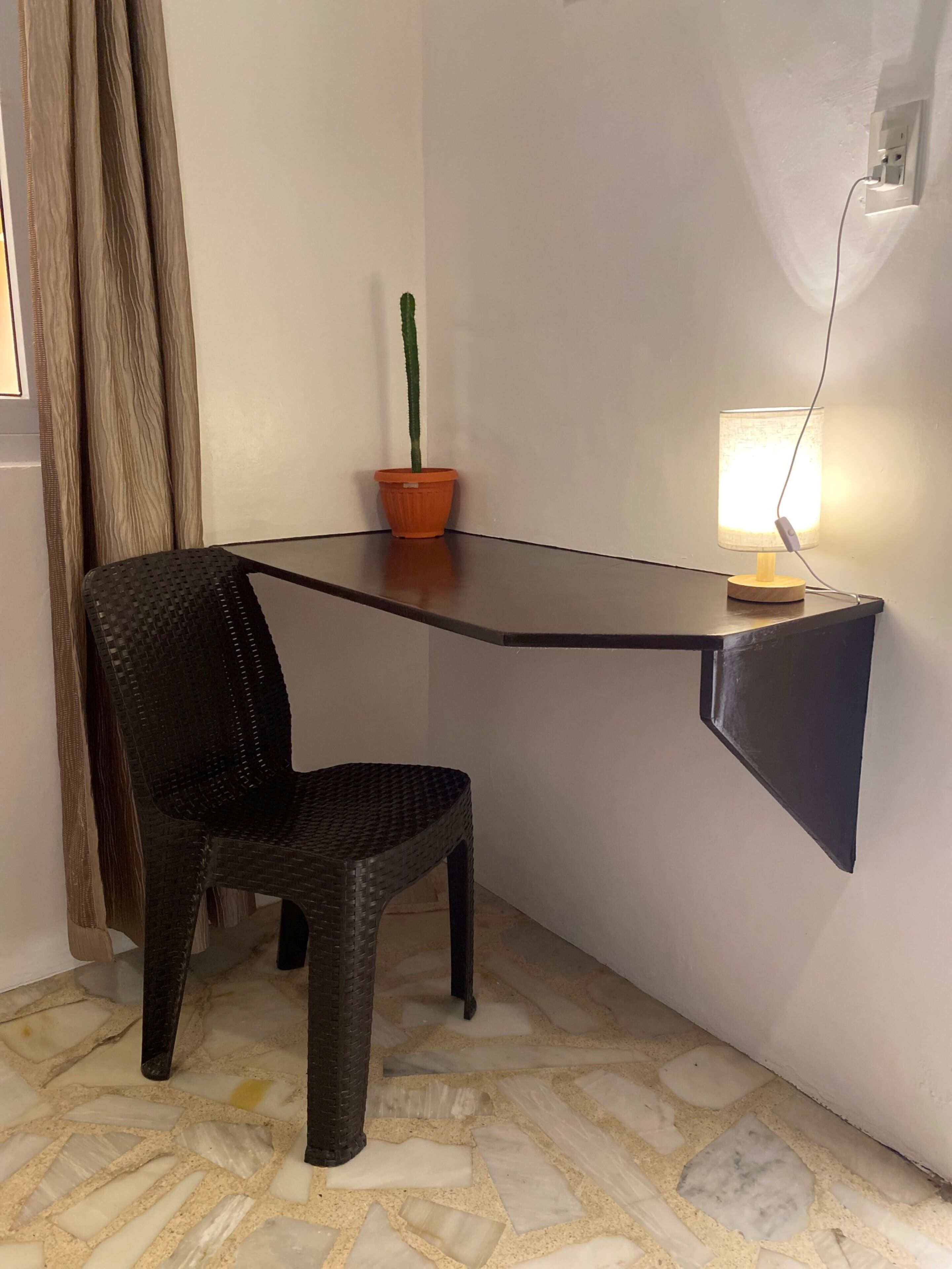 A corner desk with a chair, a potted plant, and a lamp.