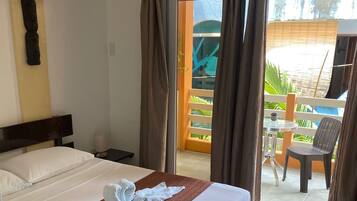 Una habitación de hotel con una cama, una mesita y un balcón con una silla.