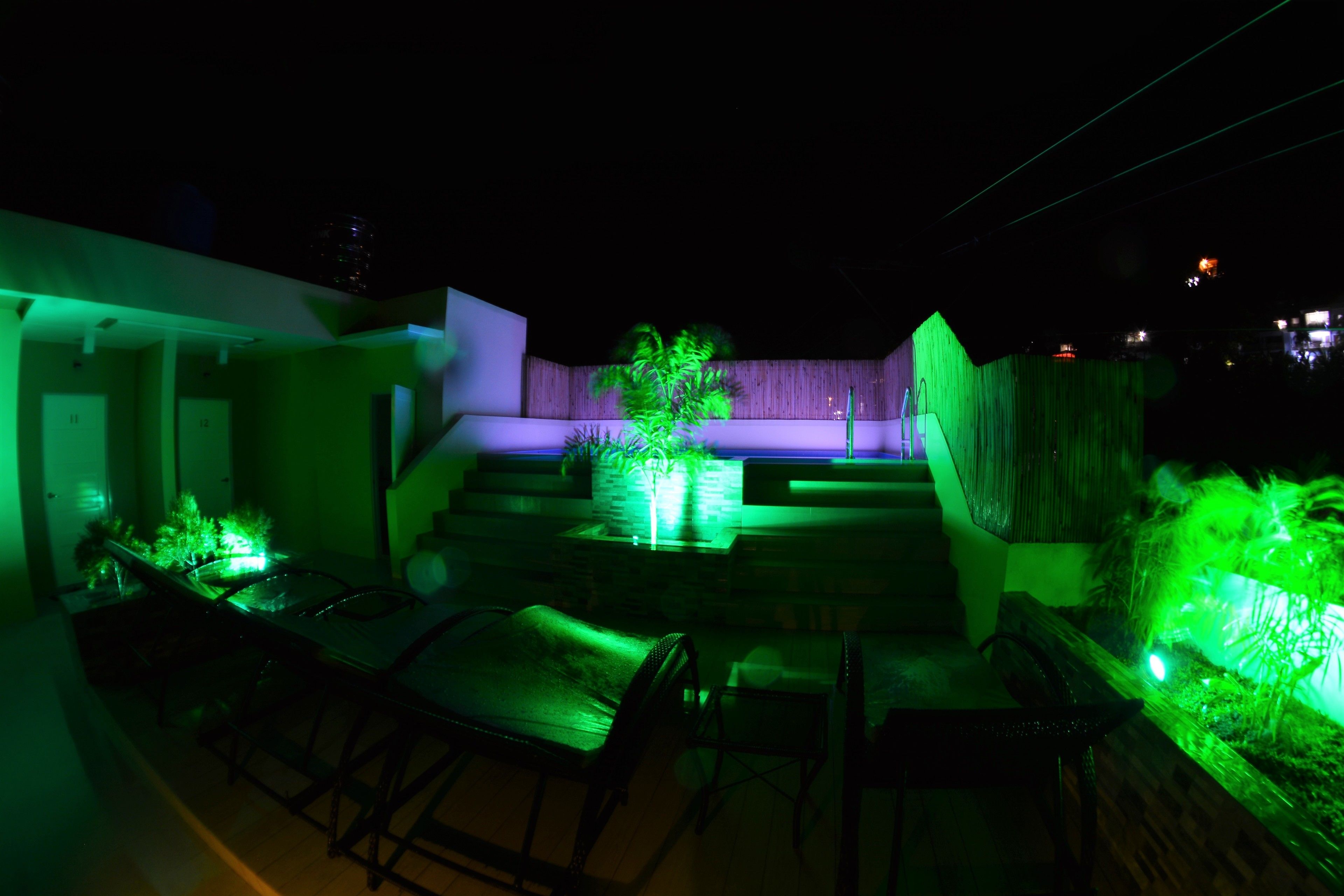 A modern outdoor patio area with a pool, seating, and a staircase leading to an upper level.