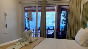 A hotel room with a bed, a view of the beach, and a sliding door to the outside.