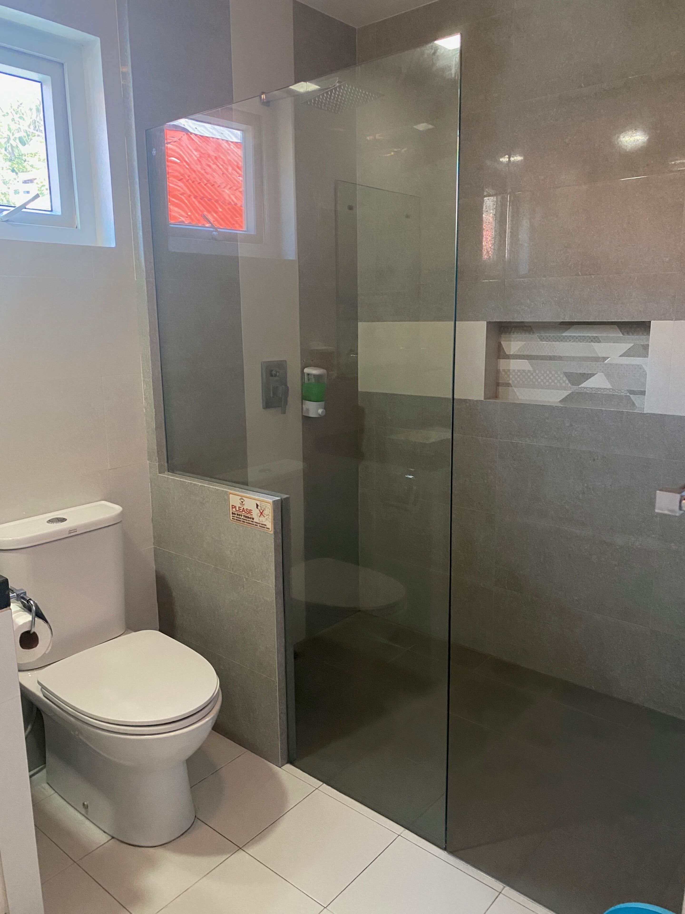 Une salle de bain moderne avec des toilettes, une douche à parois de verre et un sol carrelé.