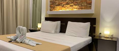 A hotel room with a bed, two bedside tables, a wall-mounted artwork, and a curtain.