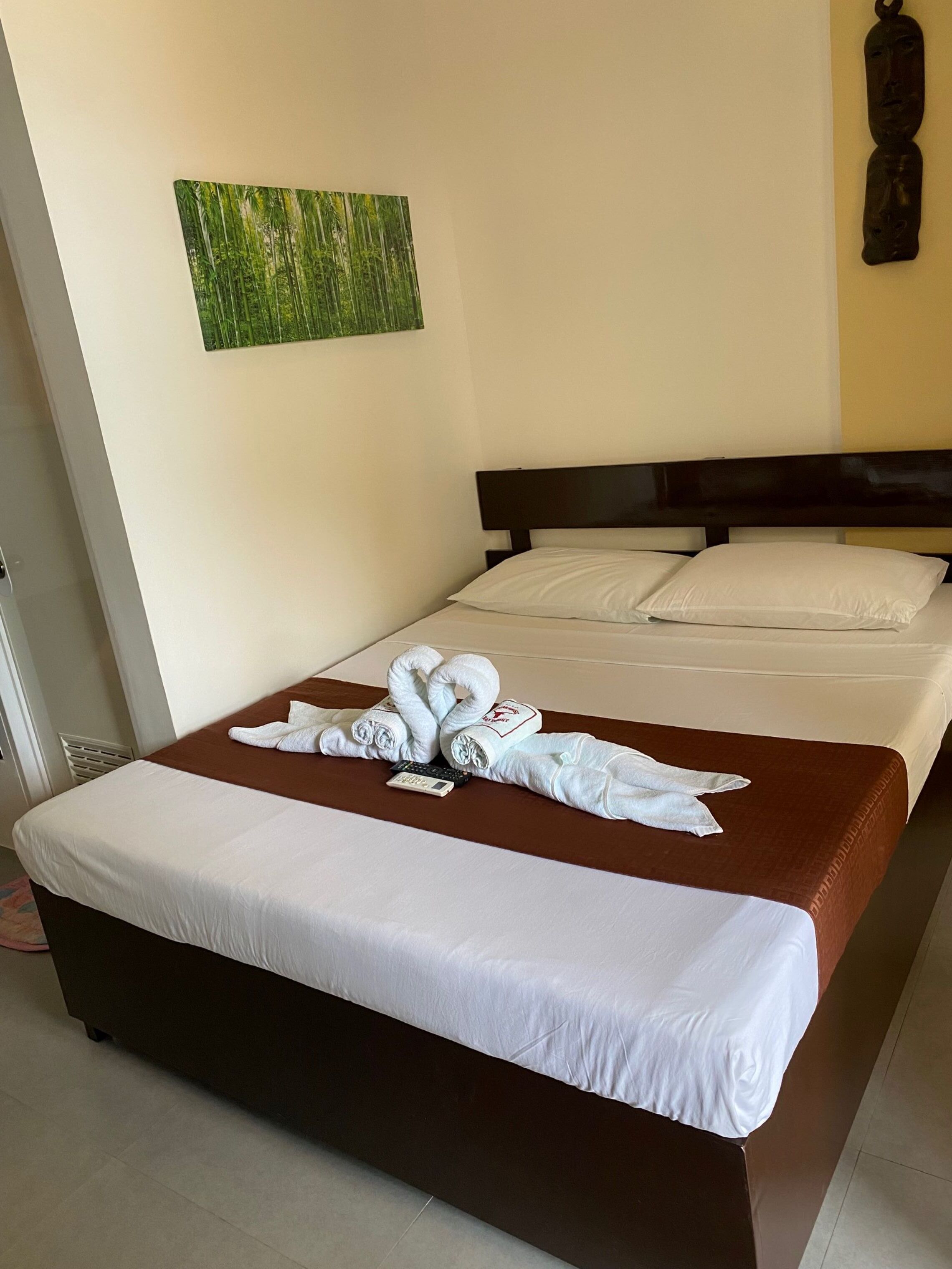 Una habitación de hotel con una cama, un cuadro en la pared y un cabecero de madera.