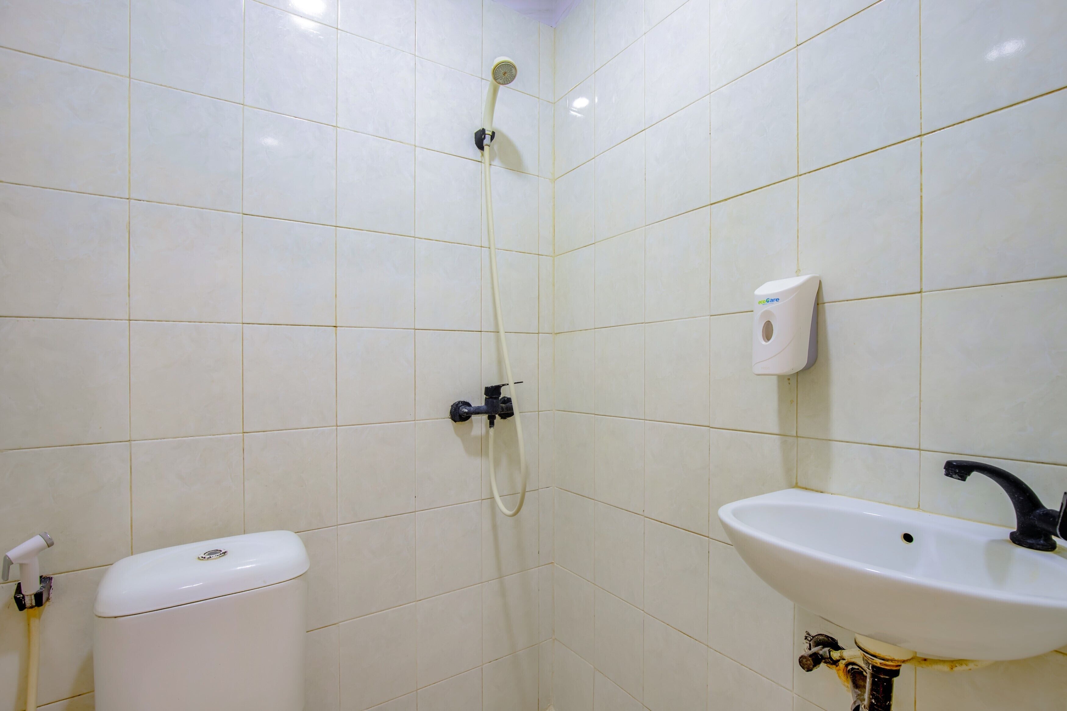 Un baño con azulejos blancos, un inodoro, un lavabo y una ducha.