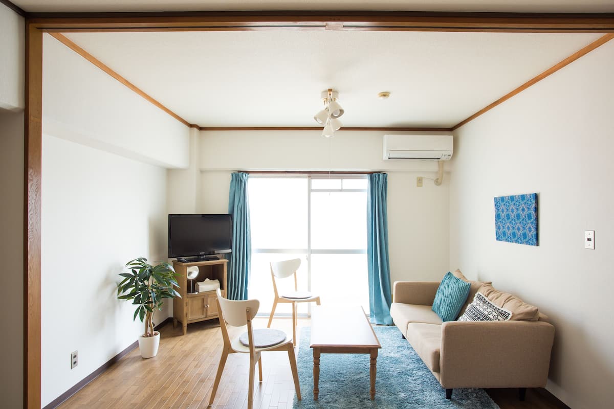 A living room with a sofa, a coffee table, a TV, and a potted plant.