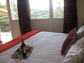 A hotel room with a bed, a bottle of wine, and a tray with oranges. - Pinetown Lala Land (Kloof)