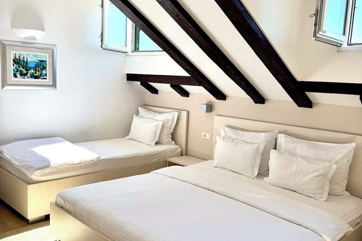 Un dormitorio con dos camas, techo inclinado y una ventana.