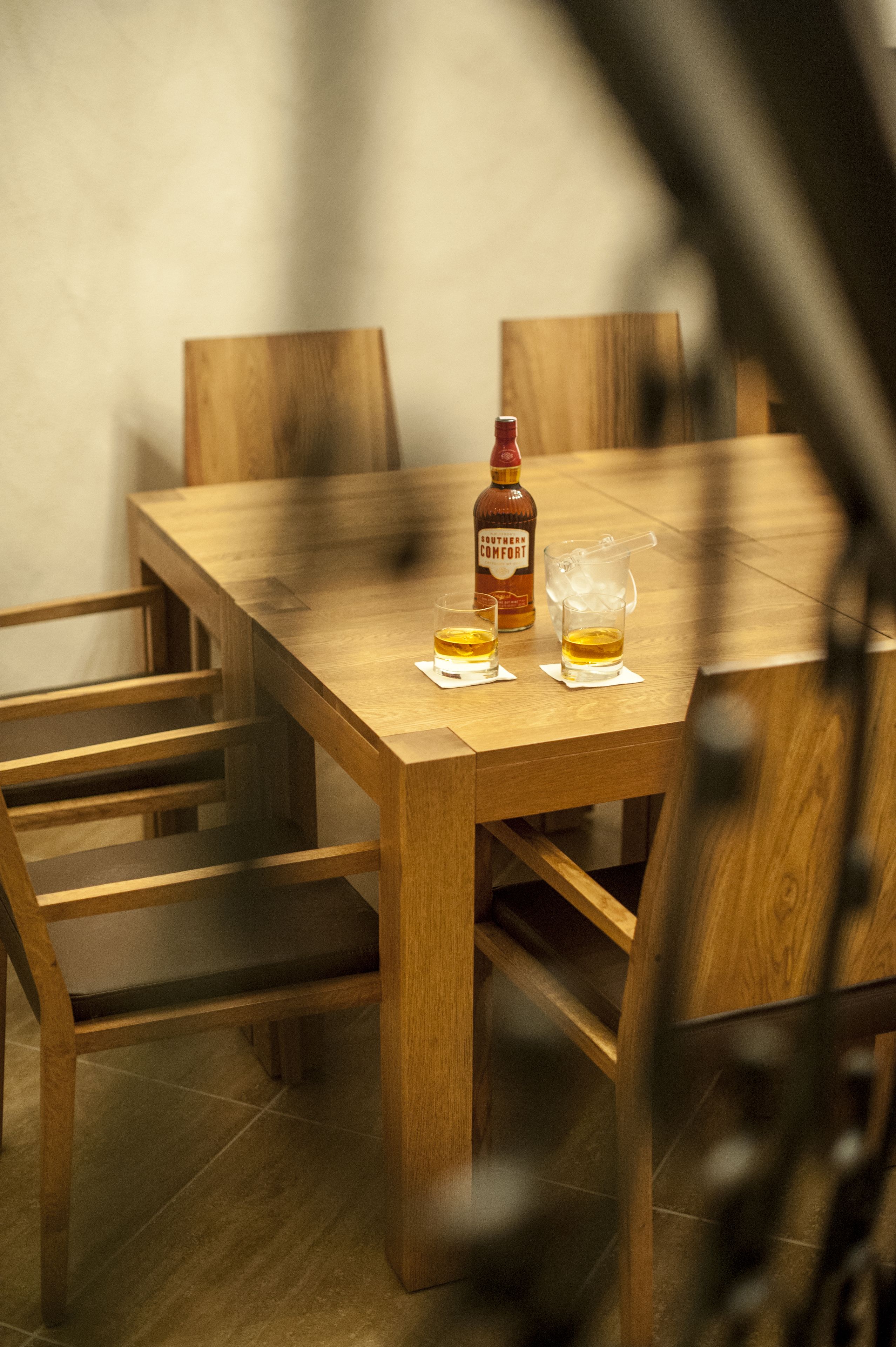 Ein Holztisch mit zwei Whiskeygläsern und einer Flasche Southern Comfort.