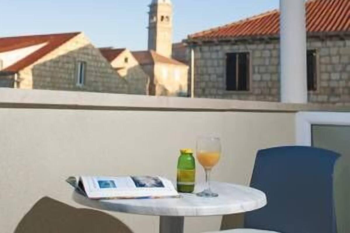 Una terraza con una mesa, sillas y vistas a una iglesia con torre.
