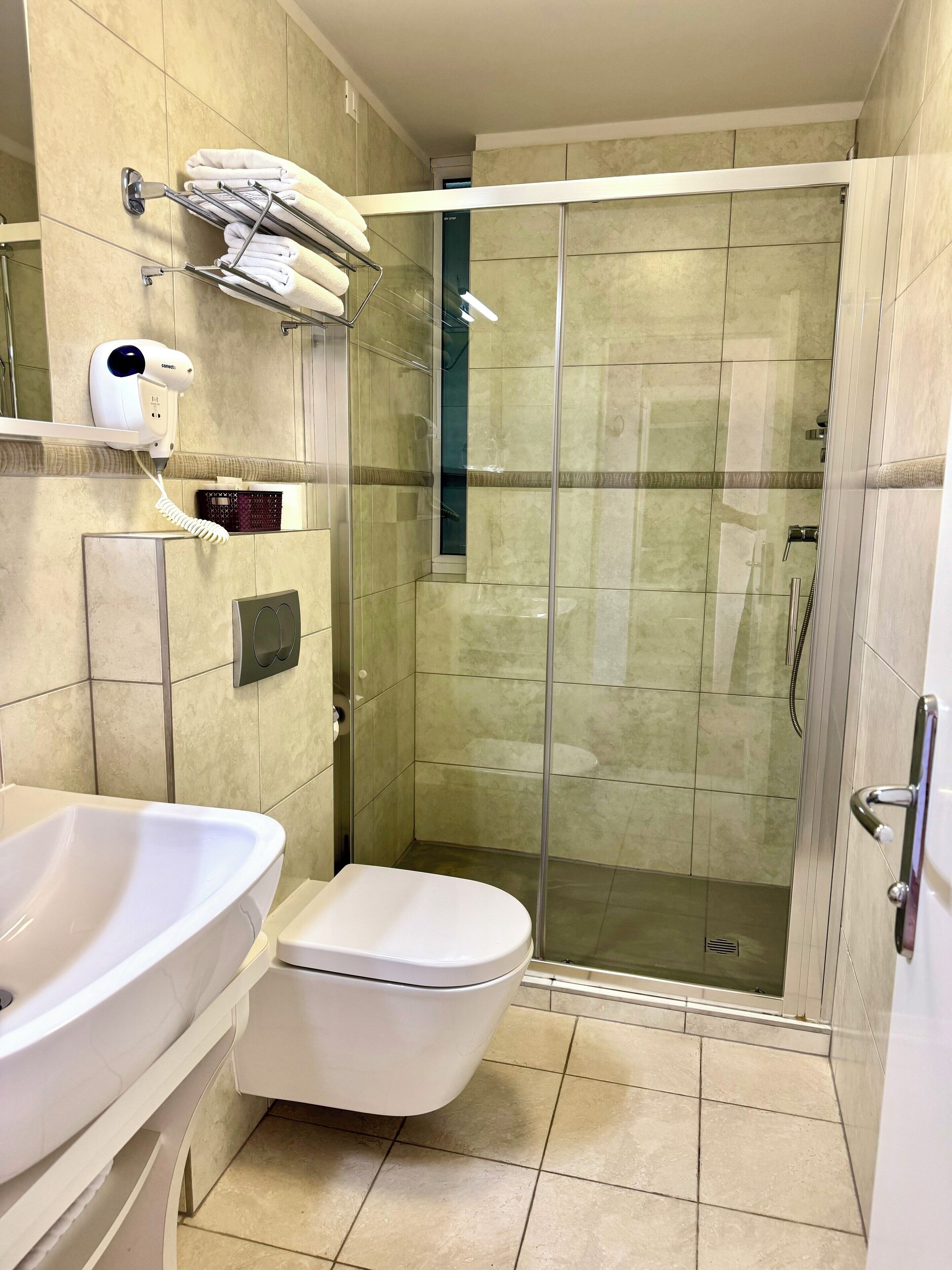 Un baño con ducha de vidrio, inodoro y lavamanos.