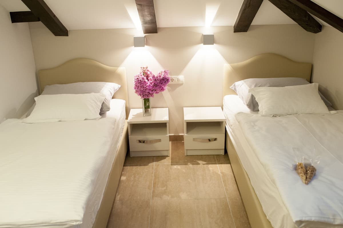 Un dormitorio con dos camas, una mesita de noche con un florero y luces fijadas en la pared.