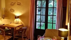 A cozy dining area with a table set for two, a window with curtains, and a lamp on the table. - La Masia Costa Brava (Garrigas)