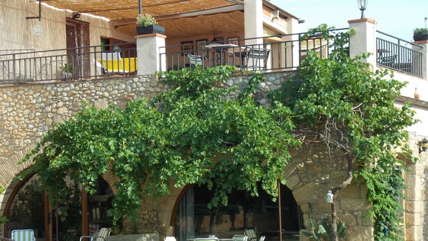 A stone building with a covered patio area featuring outdoor seating and a stone archway. - La Masia Costa Brava (Garrigas)