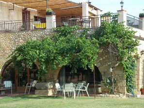 A stone building with a covered patio area featuring outdoor seating and a stone archway. - La Masia Costa Brava (Garrigas)