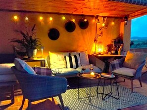 Un espacio al aire libre con sofá, sillas, una mesa y una vela.