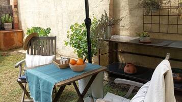 An outdoor patio with a table and chairs, a hanging plant, and a brick wall.