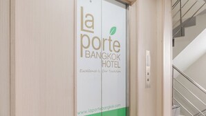 Entrada de hotel con una puerta elevadora verde y una escalera a la derecha.