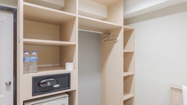 Habitación de hotel con cama, minibar, armario con espacio para colgar y un refrigerador pequeño.