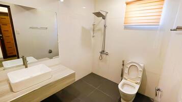 Een moderne badkamer met een grote spiegel, twee wasbakken, een douche en een toilet.