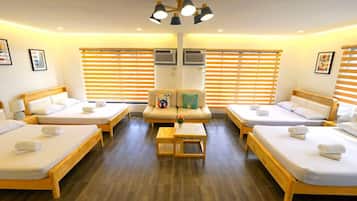 Ein Hotelzimmer mit vier Einzelbetten, einem Schlafsofa und einem kleinen Tisch.