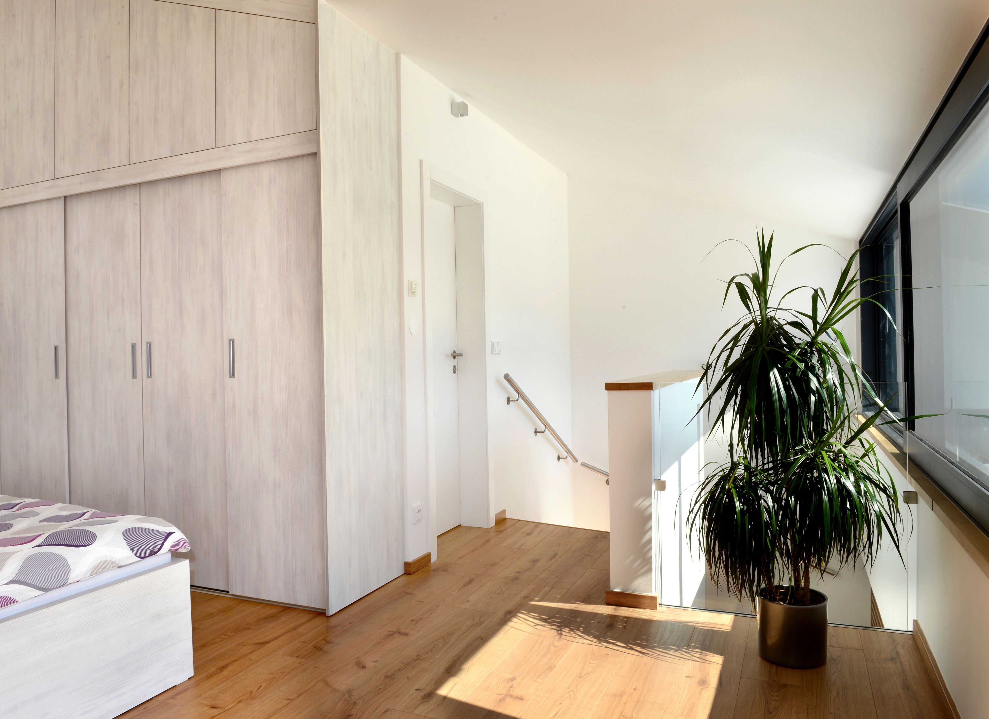 A modern bedroom with a bed, wardrobe, and a staircase leading to a balcony.