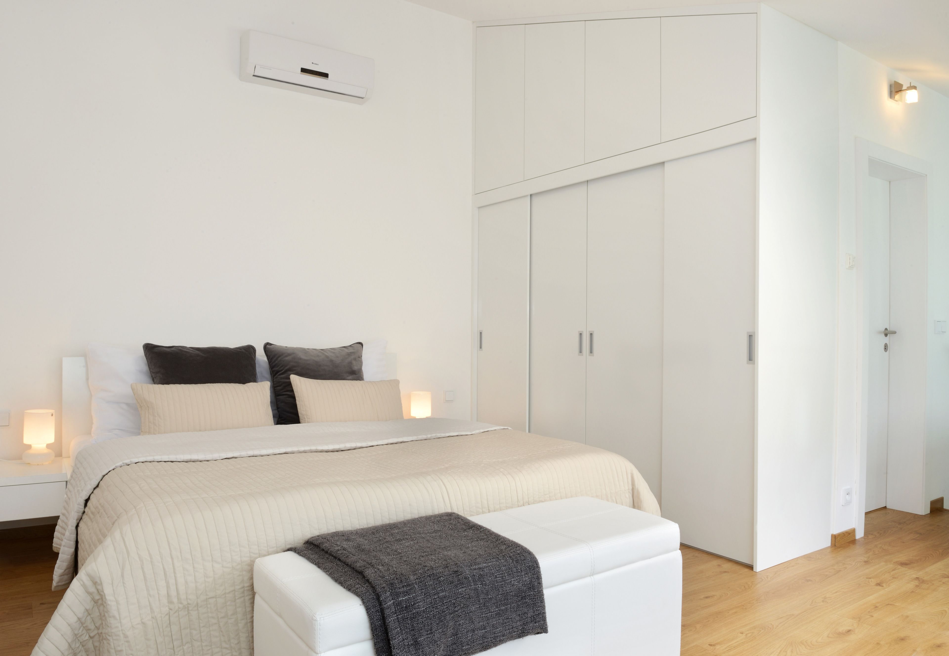 A bedroom with a bed, bedside tables, a wardrobe, and a bench.